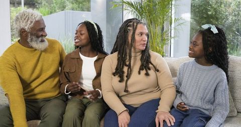 Multigenerational family chatting on sofa in bright sunlit living room