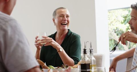 Smiling Senior Woman Enjoying Meal with Friends at Dining Table