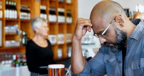 Stressed man contemplating at bar with beer