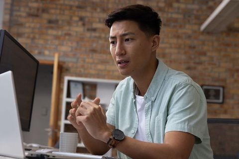 Asian man engaging in online meeting at modern workspace