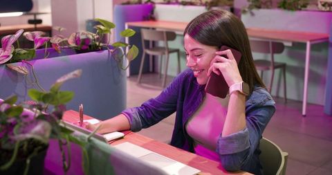 African american woman working and talking on phone in modern coworking space with plants