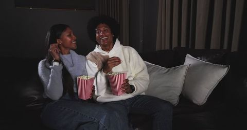 Loving Couple Enjoying Popcorn Laughing on Leather Sofa