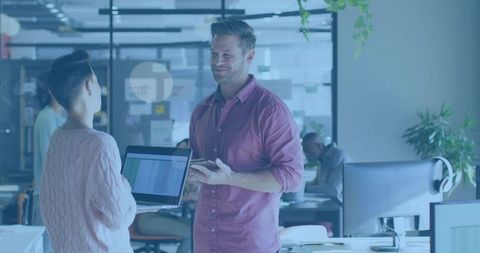 Colleagues discussing project and sharing laptop in modern open office with smartphone