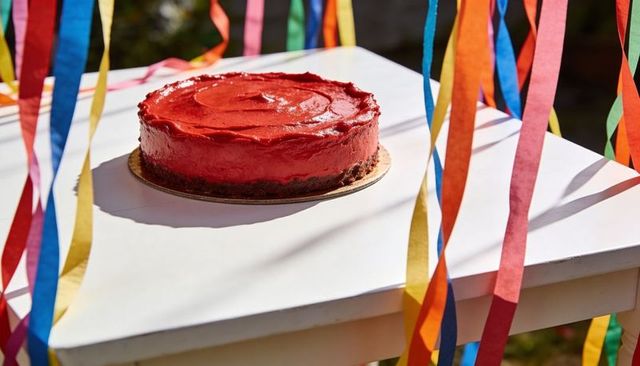 Red frosted cake on white table with colorful streamers for garden celebration