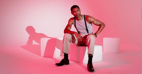 Stylish Man in Suspenders under Dramatic Pink Lighting
