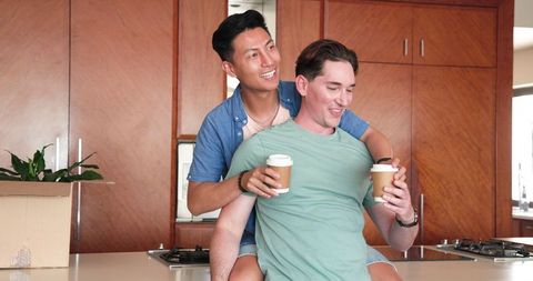 Happy Male Couple Sharing Coffee Joyfully in Modern Kitchen