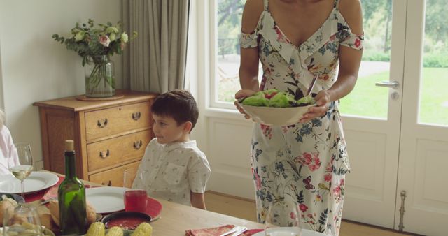 Mother Serving Salad While Young Son Stands Next to Dining Table - Download Free Stock Images Pikwizard.com