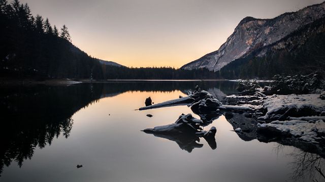 Serene mountain lake reflecting surrounding forest and twilight sky, perfect for nature-themed projects, website backgrounds, travel blogs, and relaxation apps.