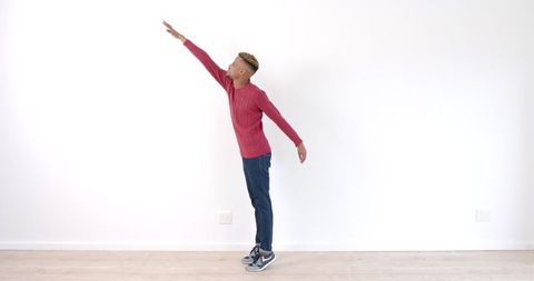 Young Man Stretching Arm Upward Indoors in Red Sweater - Download Free Stock Images Pikwizard.com