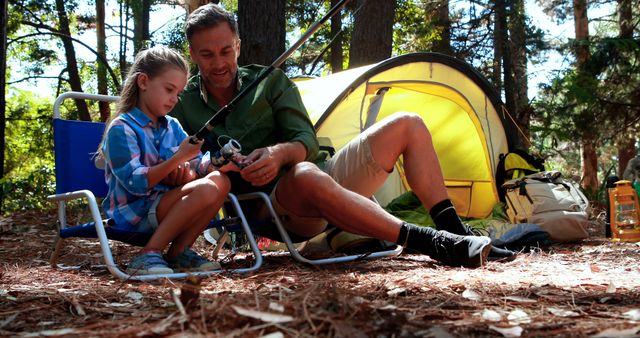 Caucasian father and daughter sitting in chairs and fishing in forest. Leisure, childhood, fatherhood, togetherness, active lifestyle, camping, nature and fishing concept, unaltered.