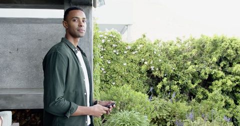 Man Standing on Garden Terrace Holding Smartphone