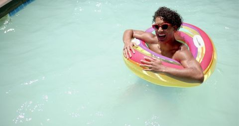 Man relaxing in pool with colorful inflatable ring on sunny day