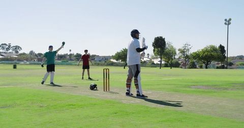 Batsman defending while bowler delivering and wicketkeeper removing bails for runout
