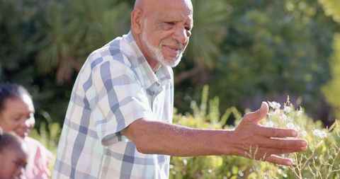 Elderly man and granddaughter gardening in sunlit backyard