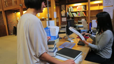 Librarian Assisting Patron at Library Circulation Desk