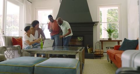 Diverse Group of Friends Laughing with Laptop by Fireplace