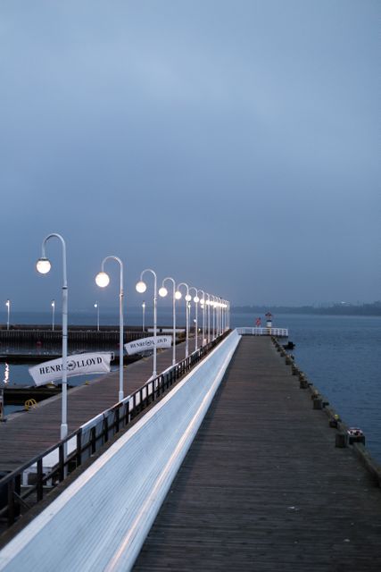 Waterfront pier illuminated in serene evening light, perfect for themes of tranquility, nature walks, and relaxation by the sea. Useful for websites or brochures showcasing coastal tourism, relaxation getaways, and peaceful waterfront areas.