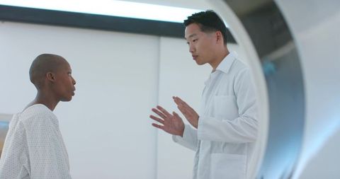 Doctor reassuring patient at ct scanner gantry during radiology consultation in hospital