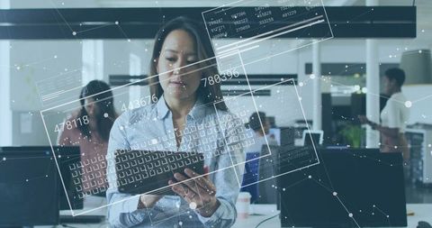 Asian professional woman using tablet with data interfaces in modern office