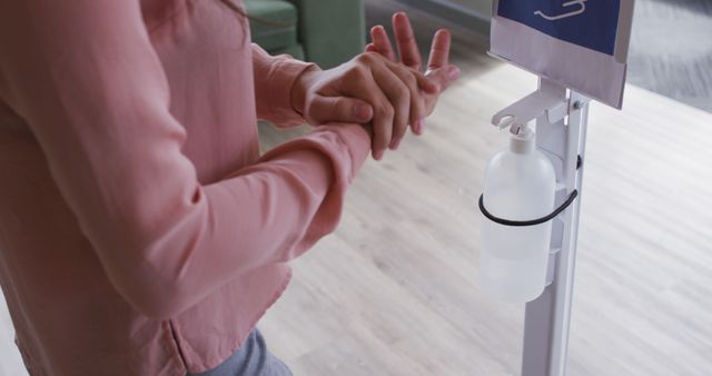 Person in Pink Top Using Hand Sanitizer in Modern Indoor Space - Download Free Stock Images Pikwizard.com