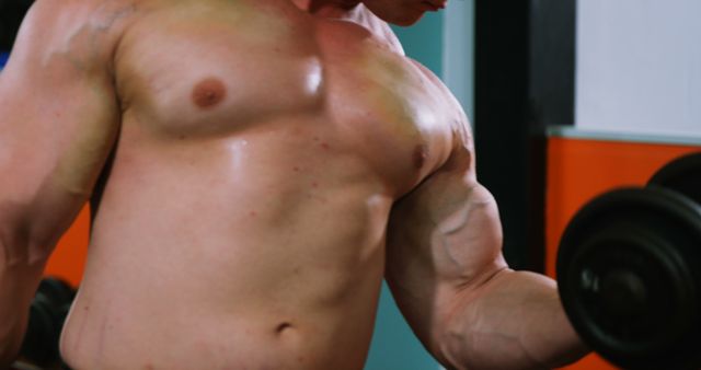 Man lifting heavy dumbbells in gym