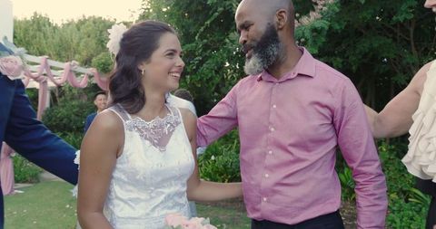 Joyous wedding celebration with guests embracing bride outdoors