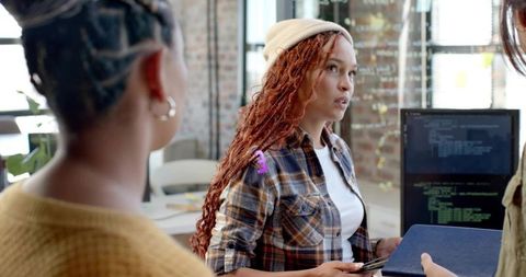 Guiding collaborative code review in modern startup office with beanie-clad developer