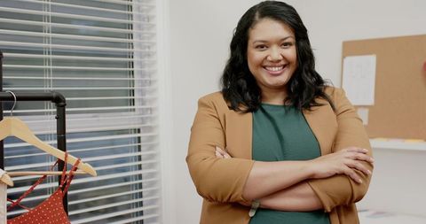 Confident boutique owner smiling with arms crossed in bright fashion studio