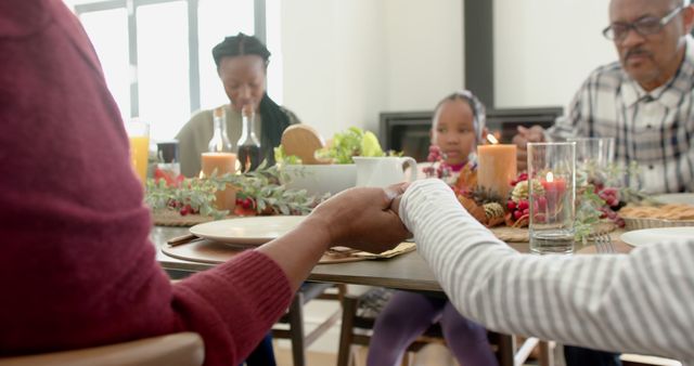 Happy african american multi generation family holding hands at thanksgiving dinner, slow motion. Thanksgiving, celebration, meal, home, family, togetherness,