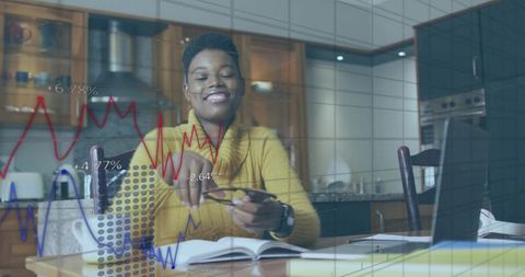 Home office woman analyzing financial charts on laptop at kitchen table with eyeglasses