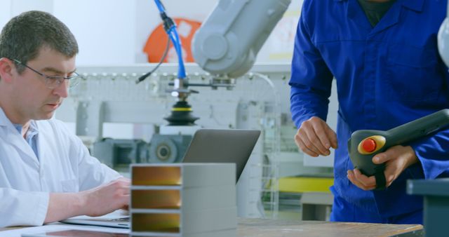 Engineer Working on Computer next to Technician Operating Robotic Arm - Download Free Stock Images Pikwizard.com