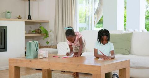 Siblings Engaged in Creative Drawing in Sunlit Living Room