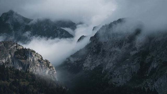 Fog-shrouding alpine valley with granite cliffs and conifer forests, mist creeping along ridges