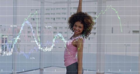 Curly-haired woman stretching in sunlit studio with fitness data graph overlay