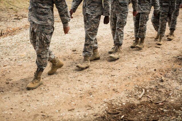 Group of soldiers in camouflage uniforms marching during a training session at boot camp. Ideal for use in articles about military training, teamwork, discipline, and preparation for service. Suitable for educational materials, recruitment campaigns, and military-themed publications.