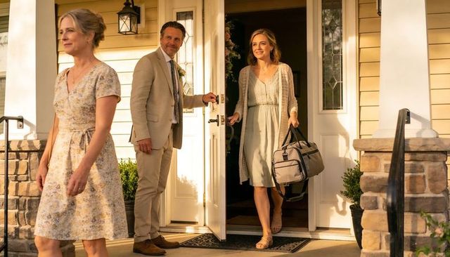 Woman stepping onto porch carrying duffel bag during golden hour