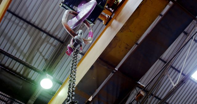 A heavy-duty crane hook hangs in an industrial setting - Download Free Stock Photos Pikwizard.com