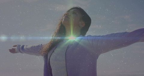 Woman standing arms outstretched embracing sunrise with cosmic lens flare dreamy pastel sky