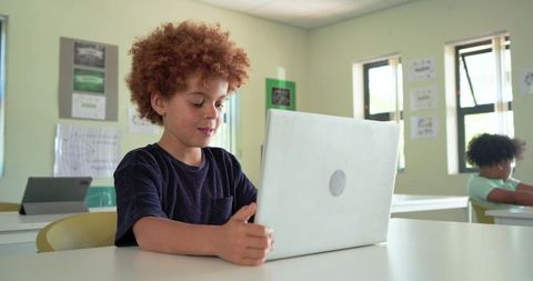 African American Boy Using Laptop in Bright Classroom Learning and Studying Digital Technology