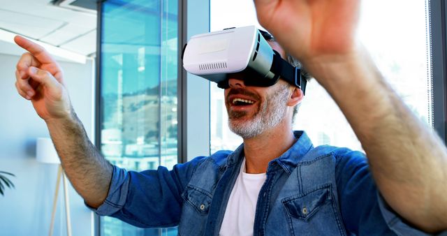 A man wearing a VR headset is smiling and actively participating in a virtual reality game. The scene captures the excitement and immersive experience associated with VR technology. Ideal for use in articles and advertising on technological advancements, VR gaming, entertainment, and cutting-edge consumer electronics.