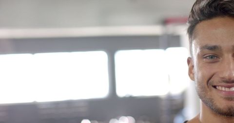 Confident Young Man Smiling in Bright Modern Gym with Copy Space