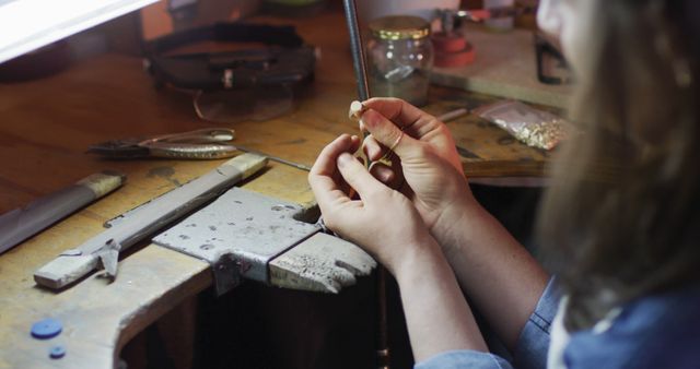 Close up of hands of caucasian female jeweller making ring in workshop. independent handmade craft business.
