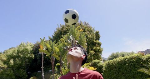 Young Man Practicing Soccer Heading Skills in Garden