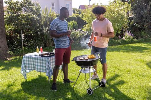 Male Friends Enjoying Backyard Barbecue Grilling Burgers