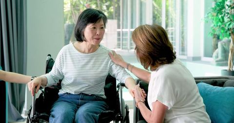 Senior Chinese Woman Chatting with Friend and Nurse in Living Room