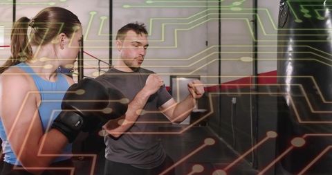 Boxing Coach Teaching Trainee Punching Technique with Circuit Overlay for Tech Fitness