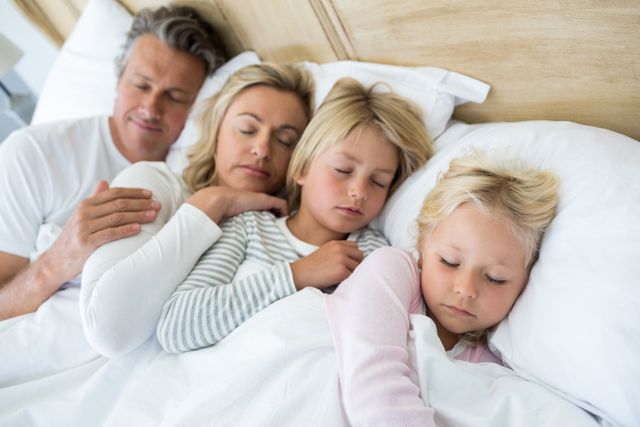 Family sleeping on bed in the bed room at home