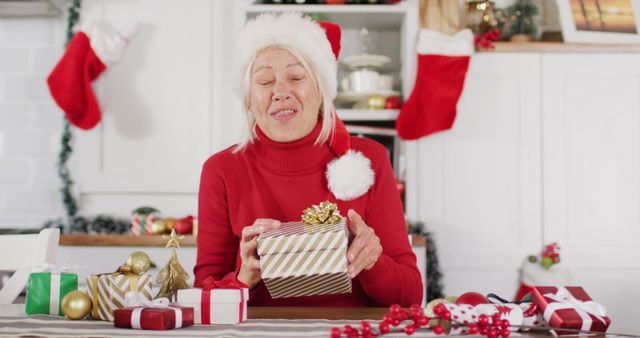 Happy senior caucasian woman wearing santa claus hat, having image call. Spending quality time at home alone at christmas.