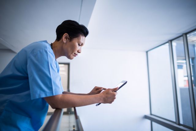 Female nurse using digital tablet in corridor of hospital