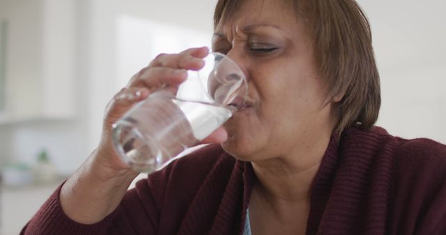 Mature Woman Drinking Water with Displeased Expression at Home - Download Free Stock Images Pikwizard.com